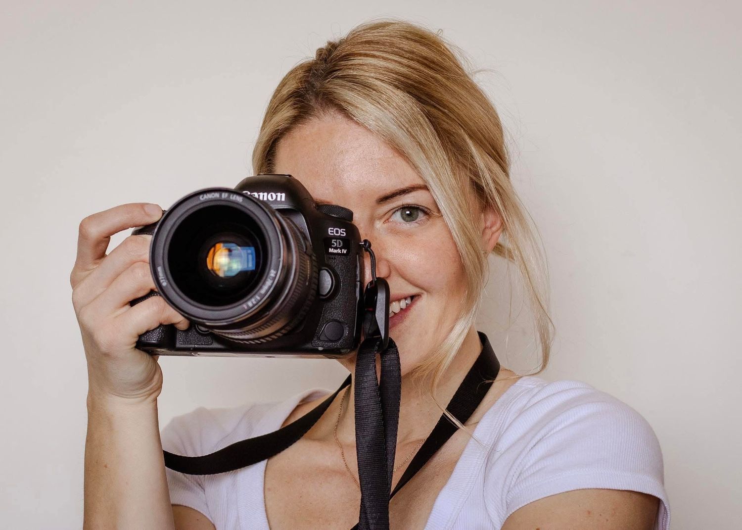 Professional photographer poses for photo holding up a canon camera.