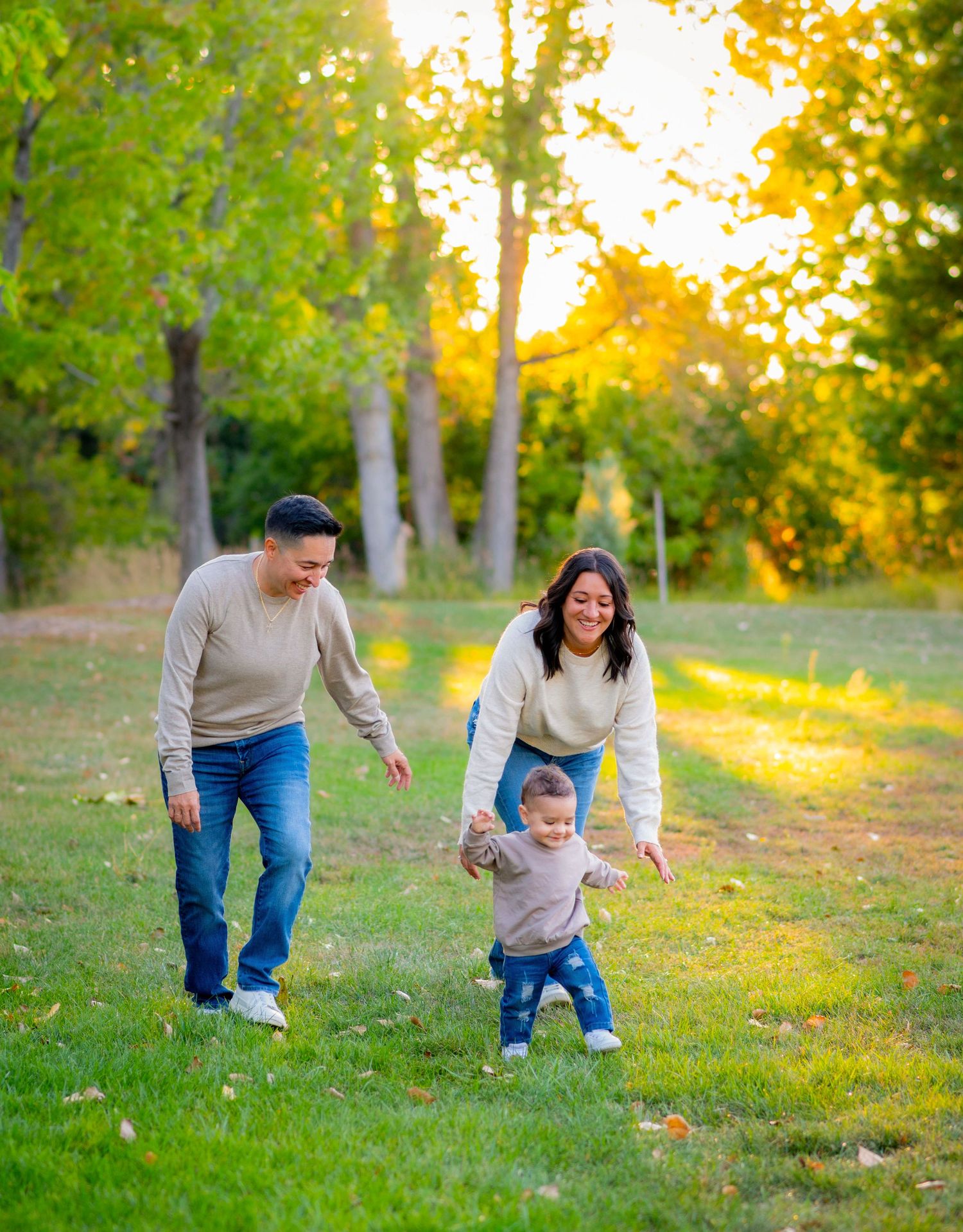 Family playing together on grassy hill during golden hour sunset.