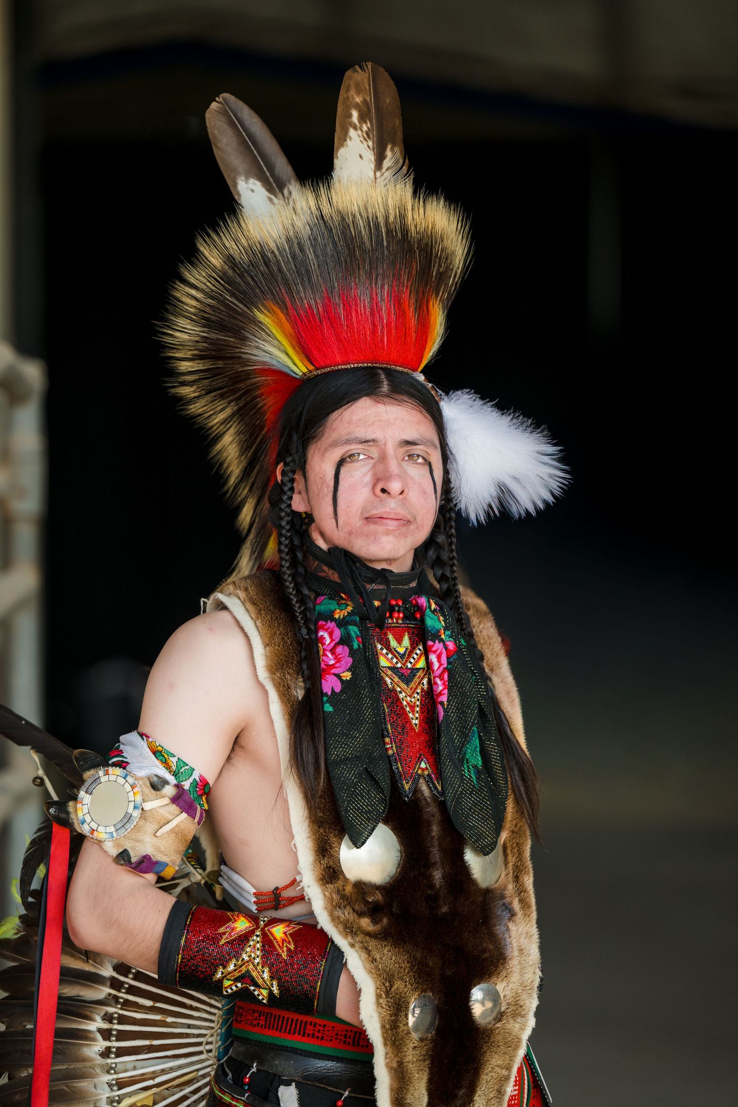 Traditional Native American dancer wearing feathered headdress and regalia with colorful decorative elements during performance.