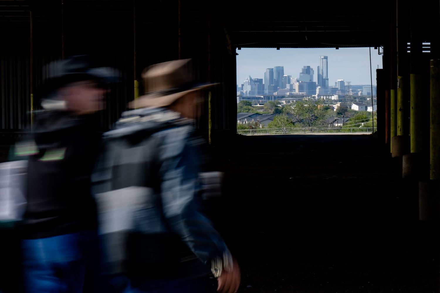 A dark interior view through a window shows the Boston skyline with skyscrapers in the distance.