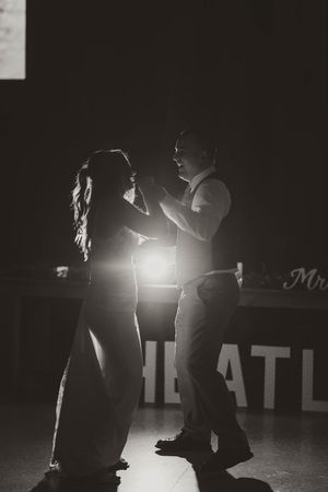 Romantic black and white silhouette of bride and groom sharing first dance at wedding reception.