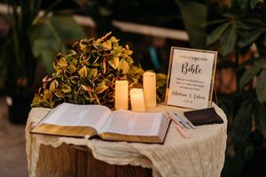 Wedding guest book Bible display with candles and hydrangeas on a rustic wooden stump.