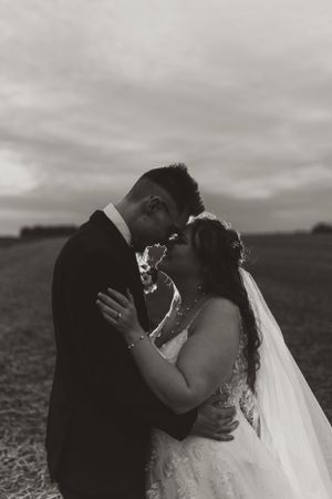 Black and white close-up of bride and groom sharing an intimate moment with veil blowing in the wind.