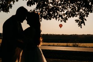Romantic silhouette of wedding couple with hot air balloon at sunset.