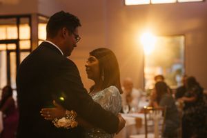 Couple shares an intimate slow dance in warm golden light during wedding reception.