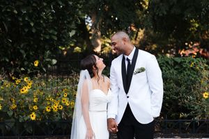 Bride and groom share a tender moment outdoors surrounded by lush greenery and sunflowers.