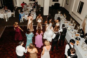Guests fill the dance floor in colorful attire during a lively wedding reception celebration.