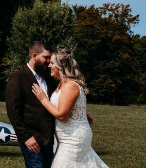 Bride and groom sharing a romantic moment outdoors near a vintage airplane on their wedding day.