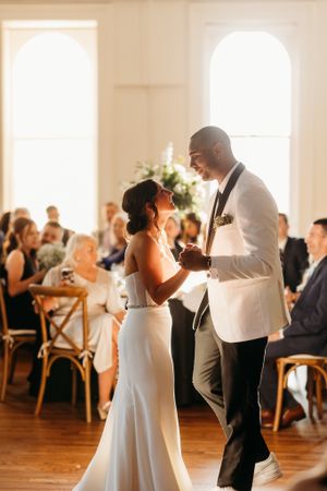 Bride and groom share their first dance in a sunlit elegant wedding reception venue.