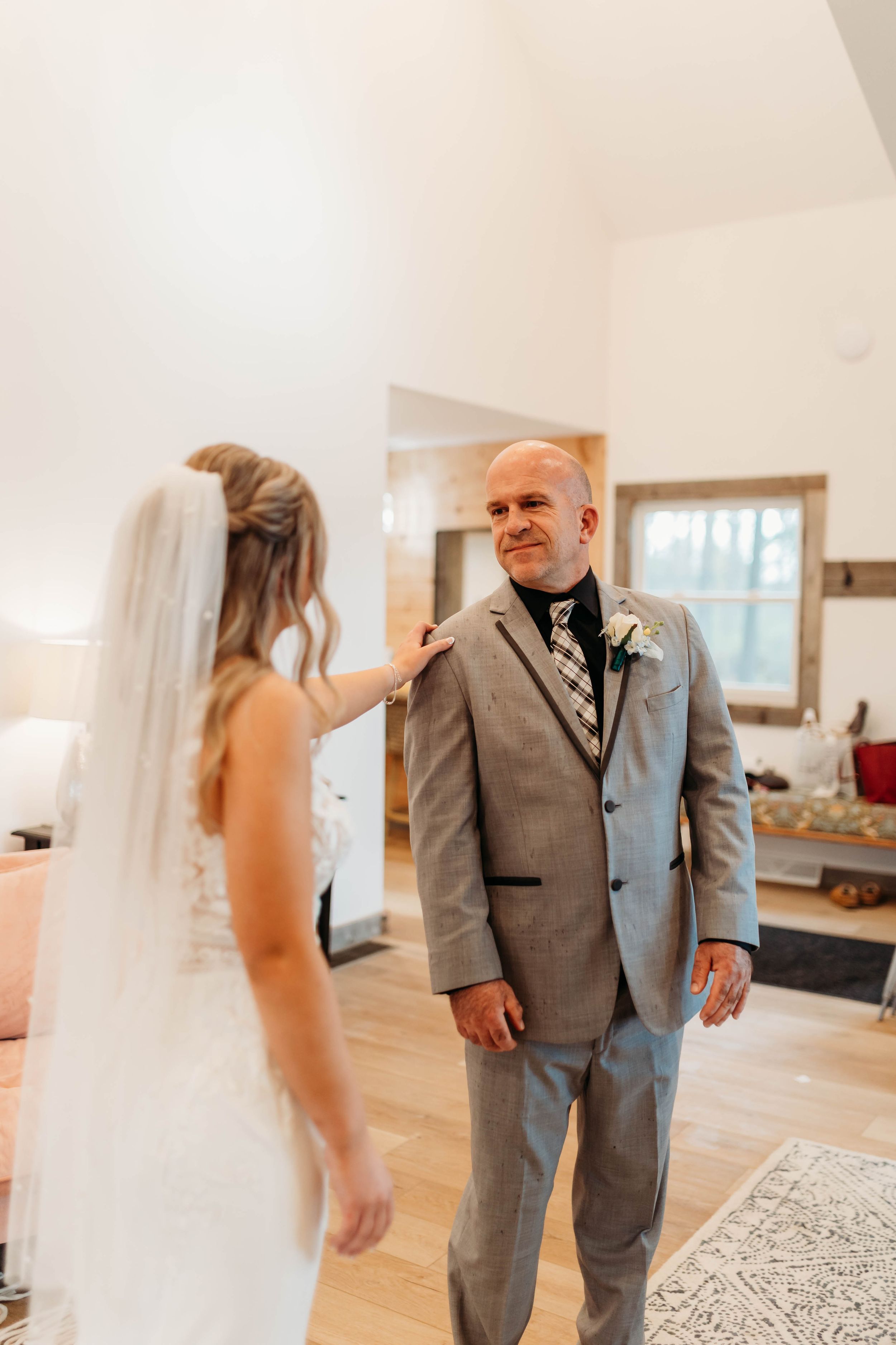Emotional father sees bride in wedding dress during first look moment.