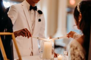 Couple lighting unity candle during elegant wedding reception ceremony.