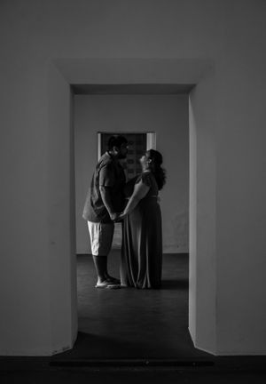Black and white silhouette of couple holding hands framed by doorway arch.