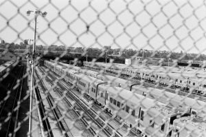Aerial view of rows of identical houses in a suburban neighborhood seen through chain link fence.