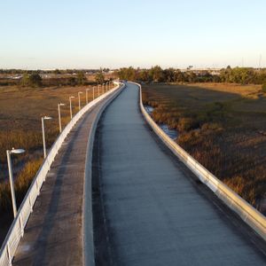 Long elevated walkway stretches across coastal marshland at dusk.