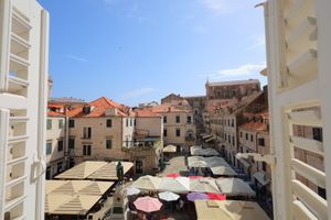 Mediterranean town square with cafe umbrellas and traditional architecture viewed from above.