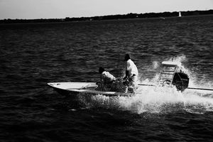 Speed boat spraying water while racing across a lake on a sunny day.