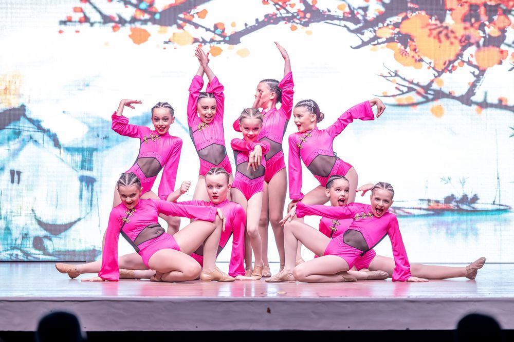 Dance troupe performs in bright pink costumes creating a dynamic group formation on stage.