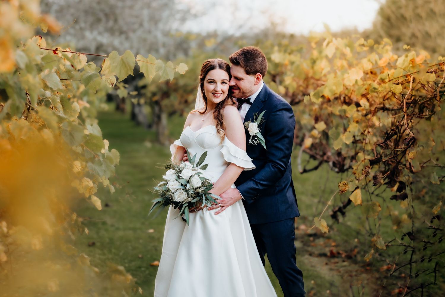 Romantic autumn wedding portrait in a vineyard with golden foliage.