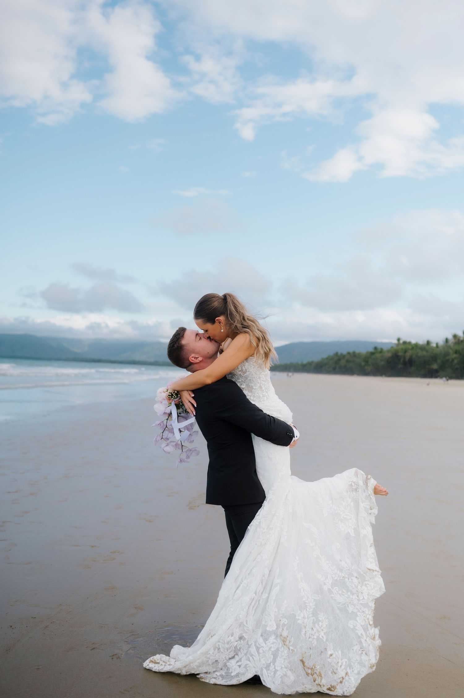 A romantic beach wedding embrace with a flowing white dress against the ocean backdrop.
