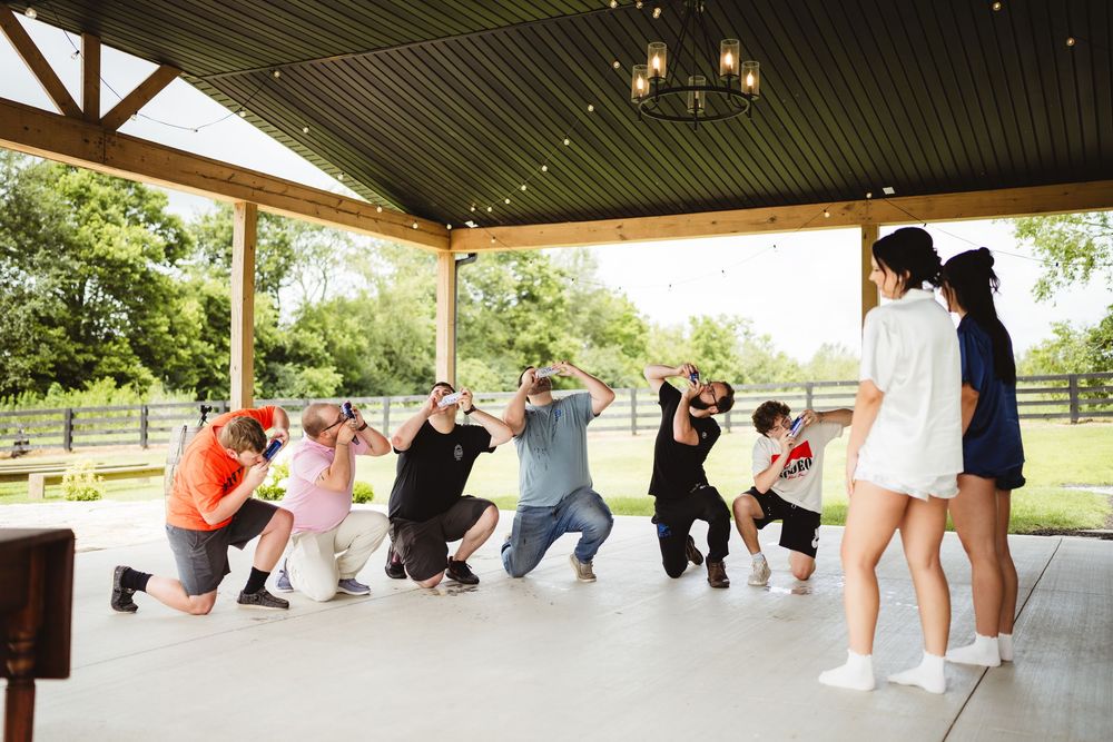 People in a line doing stretching exercises under a covered outdoor pavilion area.