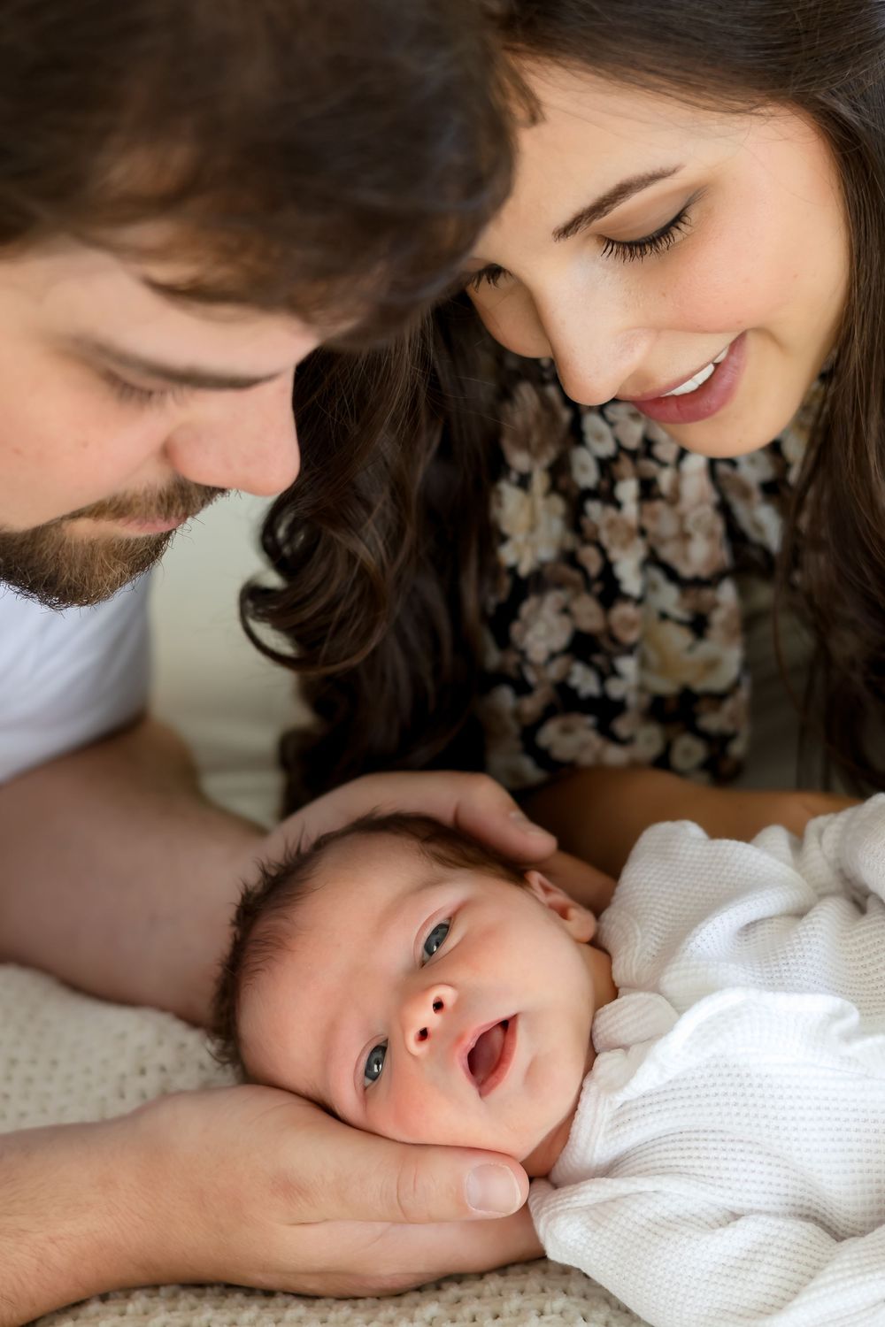 New parents smiling down at their newborn daughter during soft and natural in-studio newborn session in Athens, Georgia