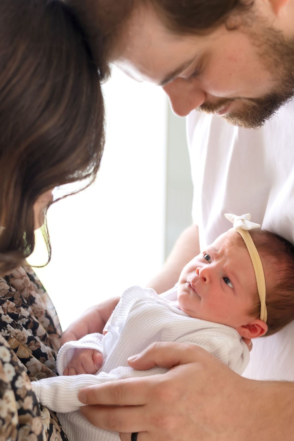 Mom and dad cradling newborn girl in arms during in-studio newborn session at Prospect Farms near Athens, GA