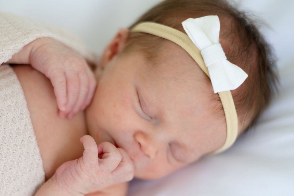Newborn girl sleeping on white bed at Prospect Farms studio near Athens GA —bright, clean, timeless photography