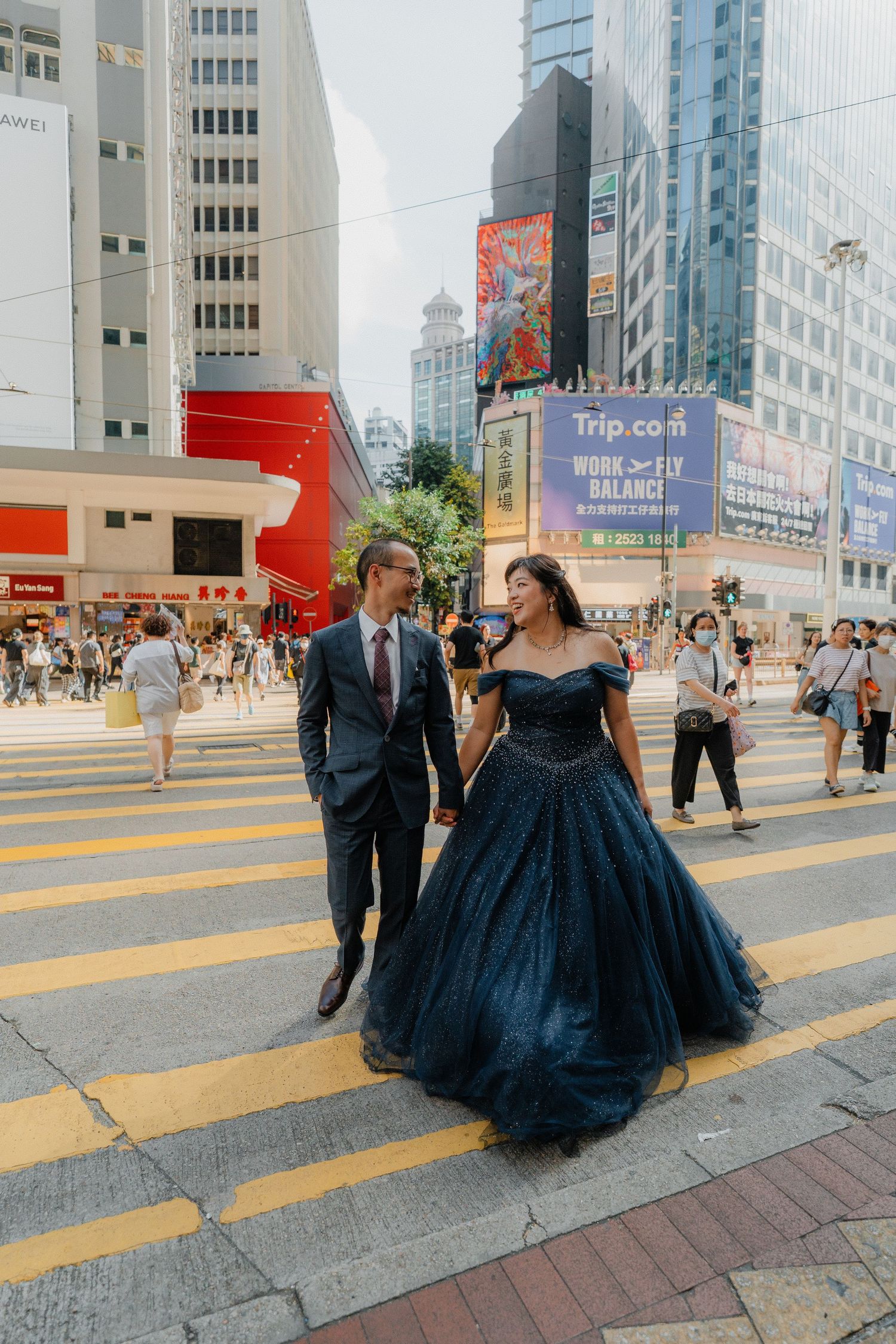 Couple walking across a busy pedestrian crossing in Hong Kong while dressed in formal attire.