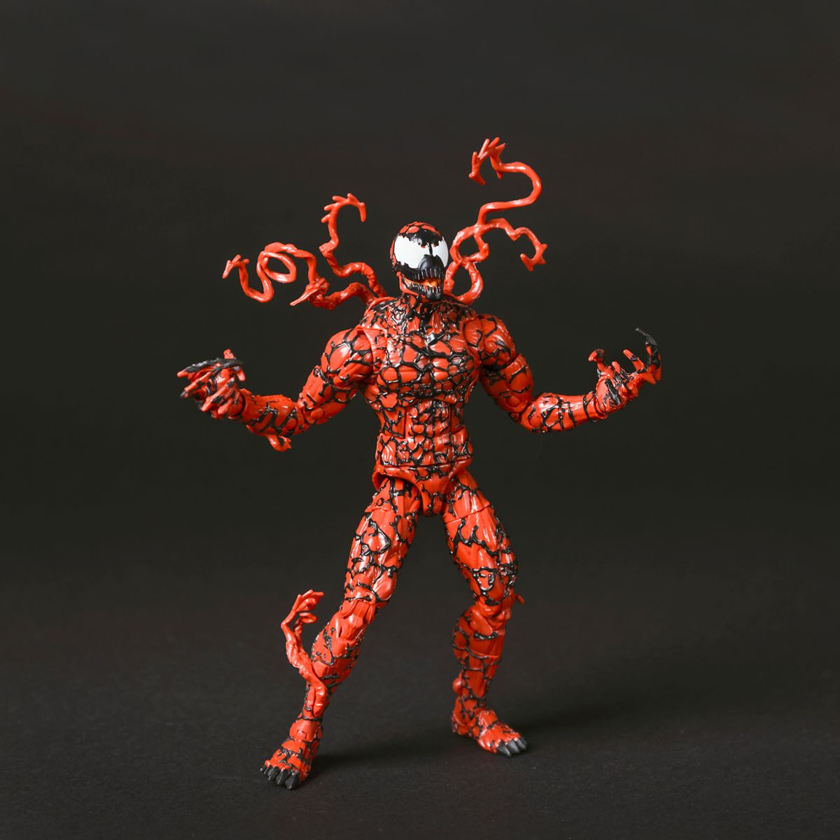 Action figure of Marvel's Carnage symbiote character in red with twisted tentacles and dynamic pose against dark background.