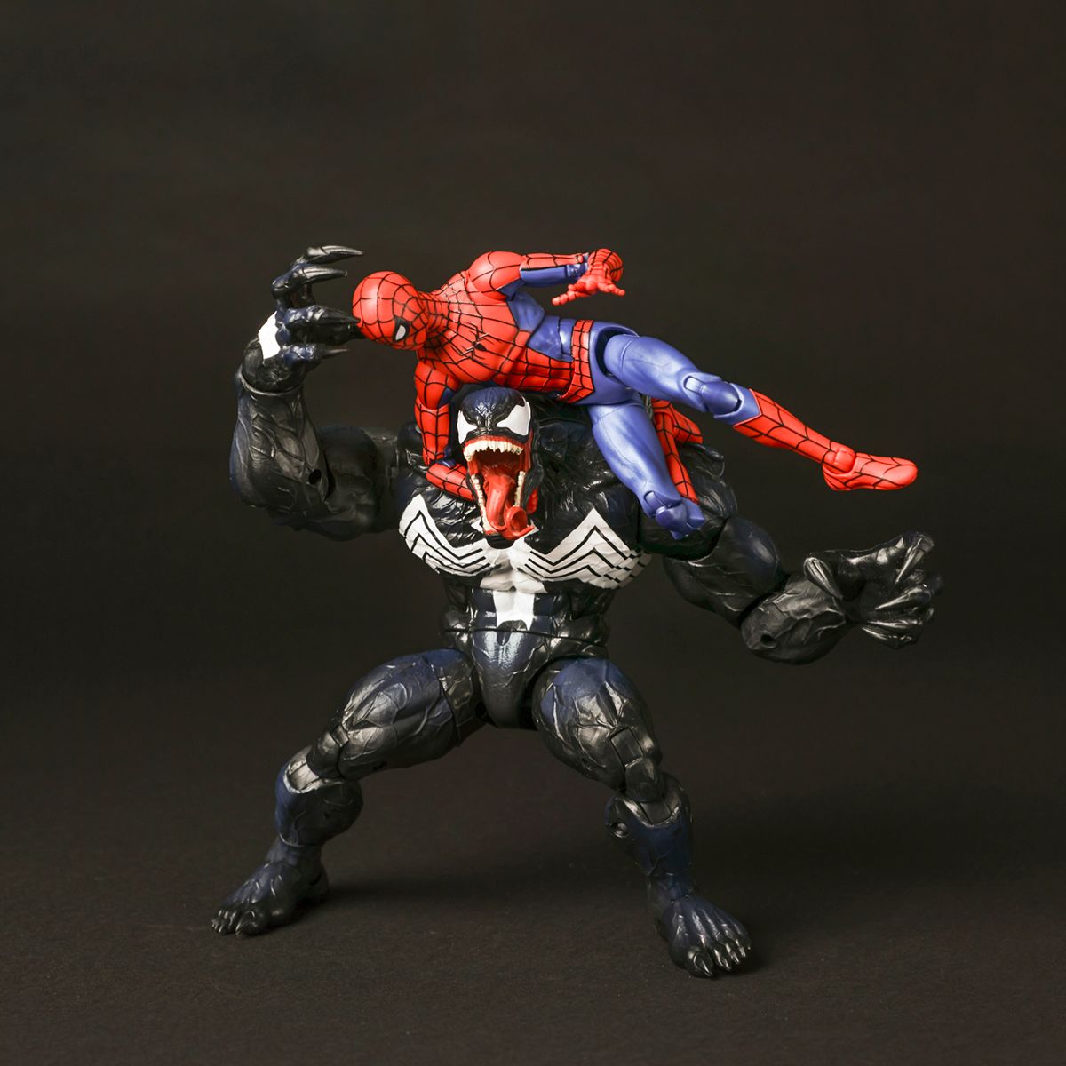 Action figure of Venom holding Spider-Man in a wrestling pose against dark background.