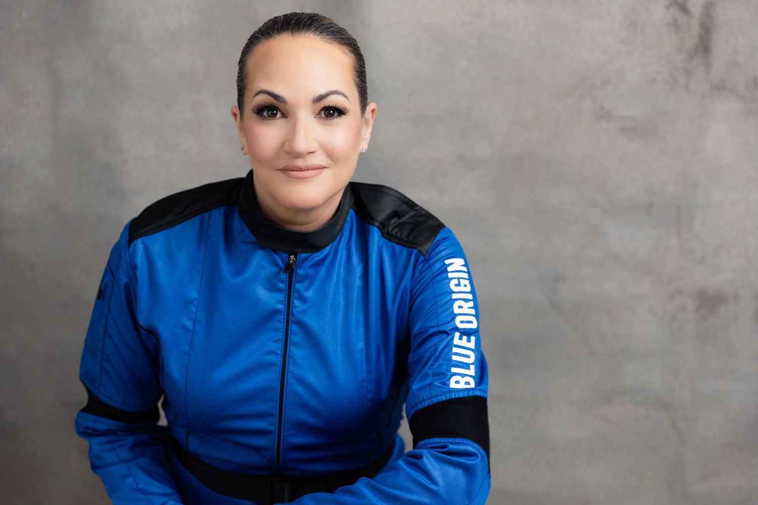 Studio photo showing a person wearing a black and bright blue sports jacket against a textured backdrop.