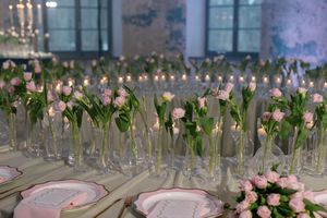 Close up images of pink tulip bouquets arranged in crystal vases create an elegant floral display at an event.