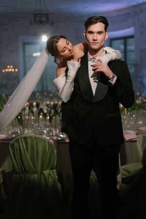 A couple in formal attire shares an intimate dance moment at an elegant wedding reception with decorative lighting.