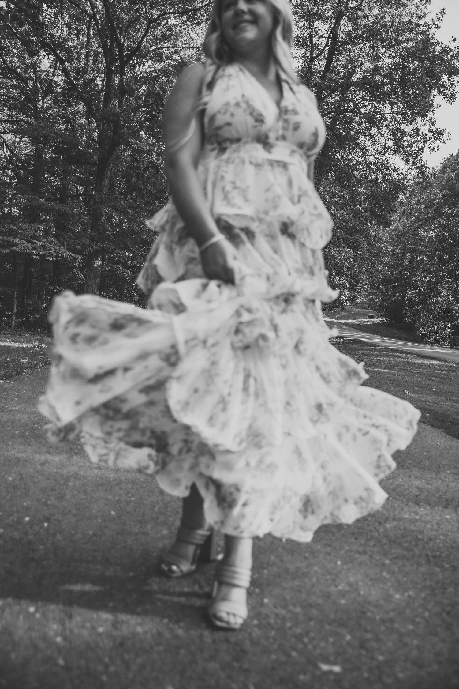 Black and white photo of flowing floral dress twirling in outdoor setting.