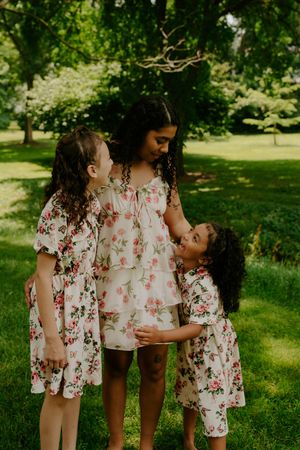 A sweet candid moment captured of three people in matching floral outfits embracing outdoors.