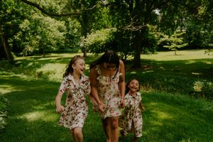 Three people in coordinating floral dresses enjoy a sunny day in the park together.