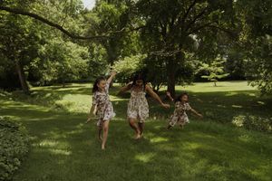 Kids in matching floral dresses enjoy a summer day in a lush park setting.
