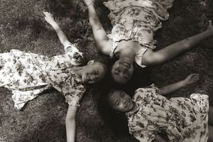 Artistic black and white photo of children relaxing on ground in summer.