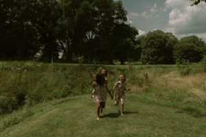 People walking through a lush green field on a bright cloudy day.