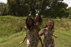 Two people in floral dresses enjoying a sunny summer day in a grassy meadow.