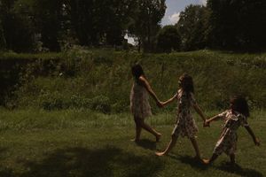 People walking together through a scenic grassy field surrounded by trees.