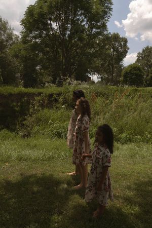 Two figures in floral dresses explore a wild meadow on a summer afternoon.