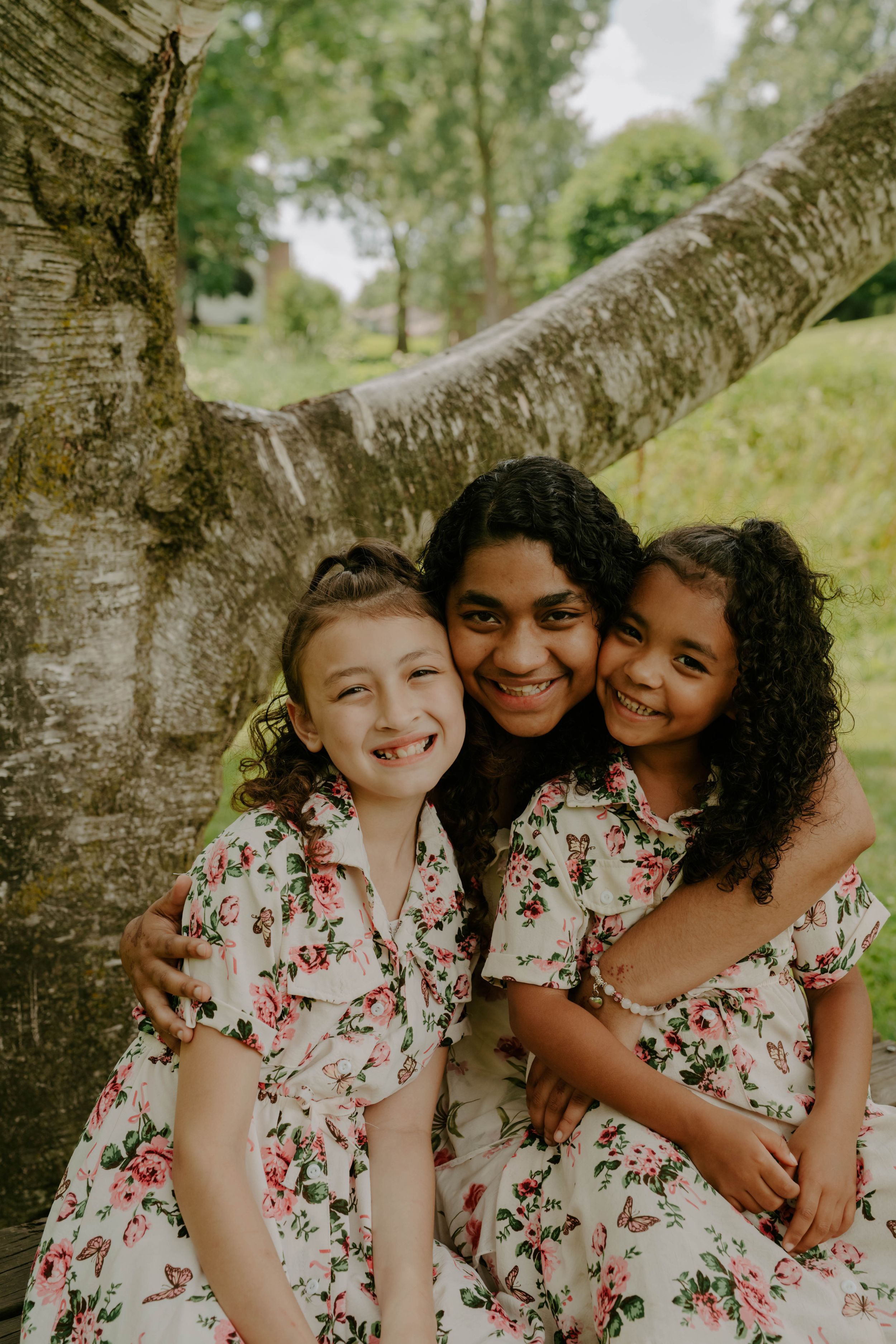 Candid portraits showing genuine joy and connection while sitting by a large tree.