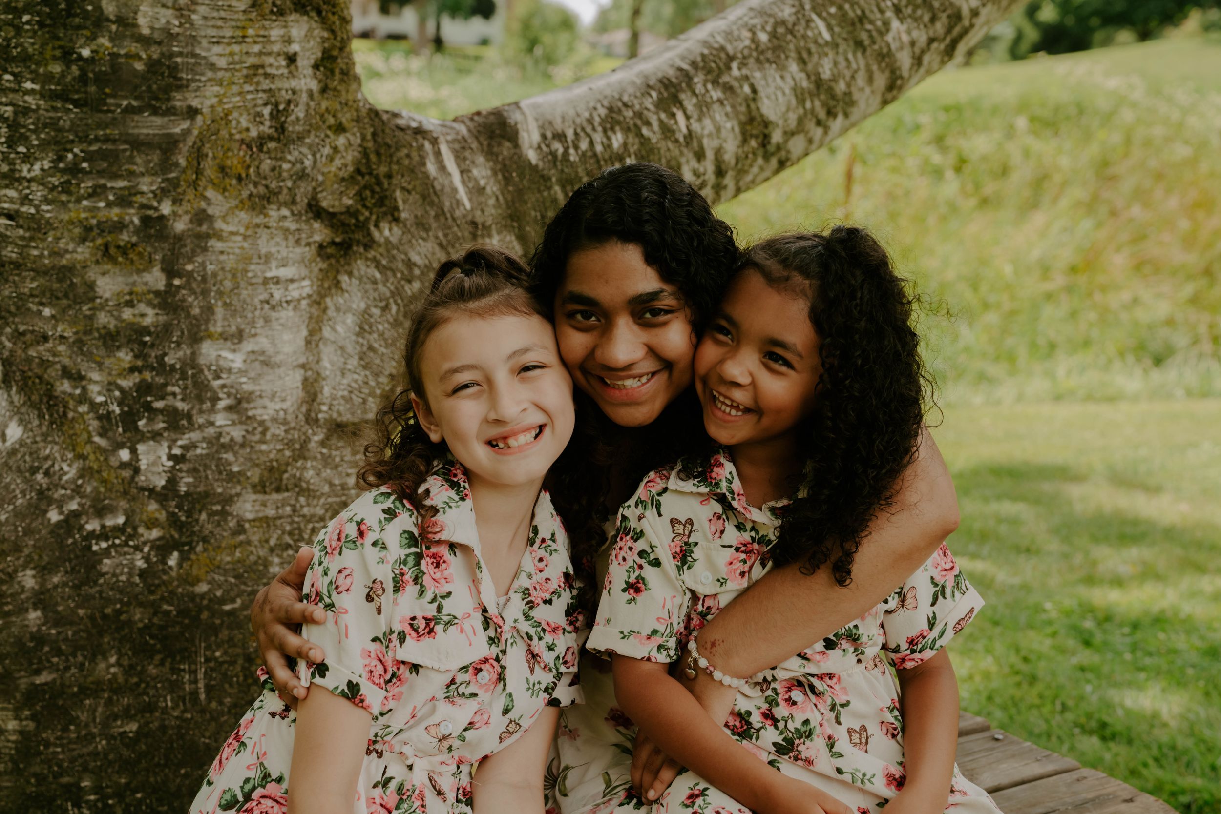 Sweet candid moments captured against a rustic tree backdrop in a park.
