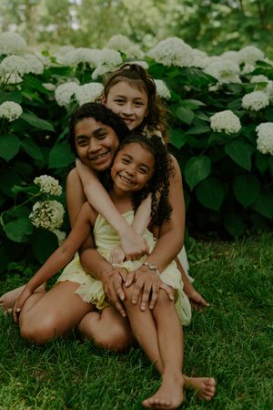 Casual outdoor photo of children sharing laughs while sitting on green grass.