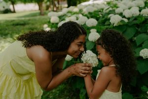 Playful interaction between children in yellow dresses among blooming hydrangeas.