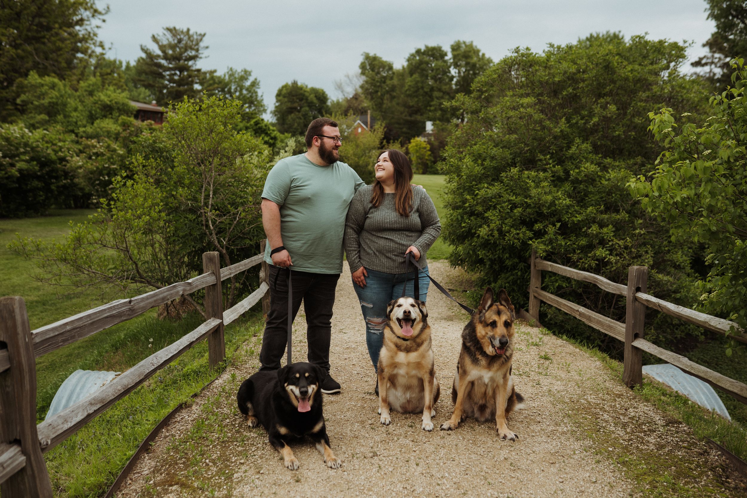 A group enjoys a spring day outdoors with their German Shepherd and other dogs on a wooden walkway.