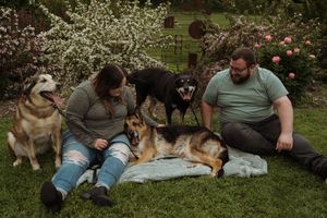 Candid moments of companions relaxing with their dogs on a blanket during a spring photoshoot.