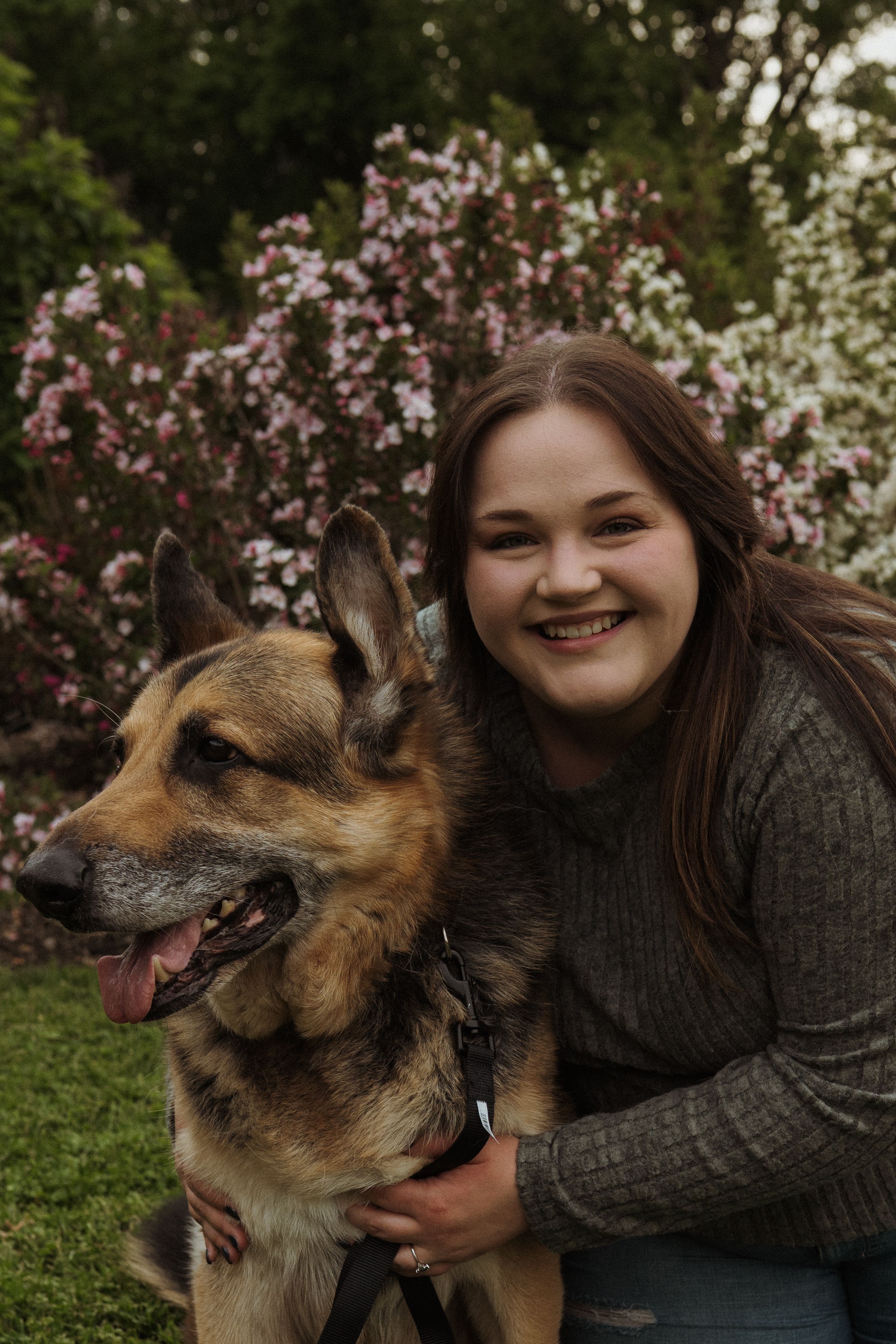 German Shepherd mix dog and companion sharing joyful moment in garden setting.