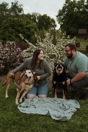 Candid family moment with pets relaxing on blanket in flowering garden.